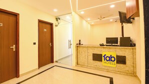 A hotel reception area with a marble counter, a ceiling fan, and a sign for 'fab hotels'. - Fabhotel Pvs Grand (New Delhi)