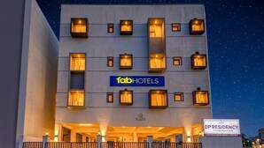 Un bâtiment moderne doté de nombreuses fenêtres illuminées, d’une enseigne « fabHOTELS » et d’une autre enseigne « DP RESIDENCY ».