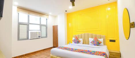 A bedroom with a bed, a ceiling fan, a window with blinds, and a yellow wall.