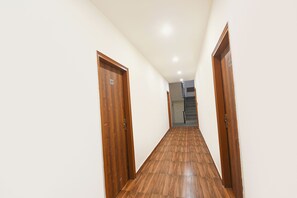Un pasillo con puertas de madera, una escalera y piso de baldosas.