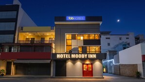 Ett modernt hotell med en framträdande skylt, en balkong och en väl upplyst entré.