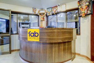 A reception desk with a wooden finish and a yellow sign reading "fab HOTELS".