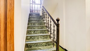 Escadaria com degraus de mármore e grades de metal decoradas.