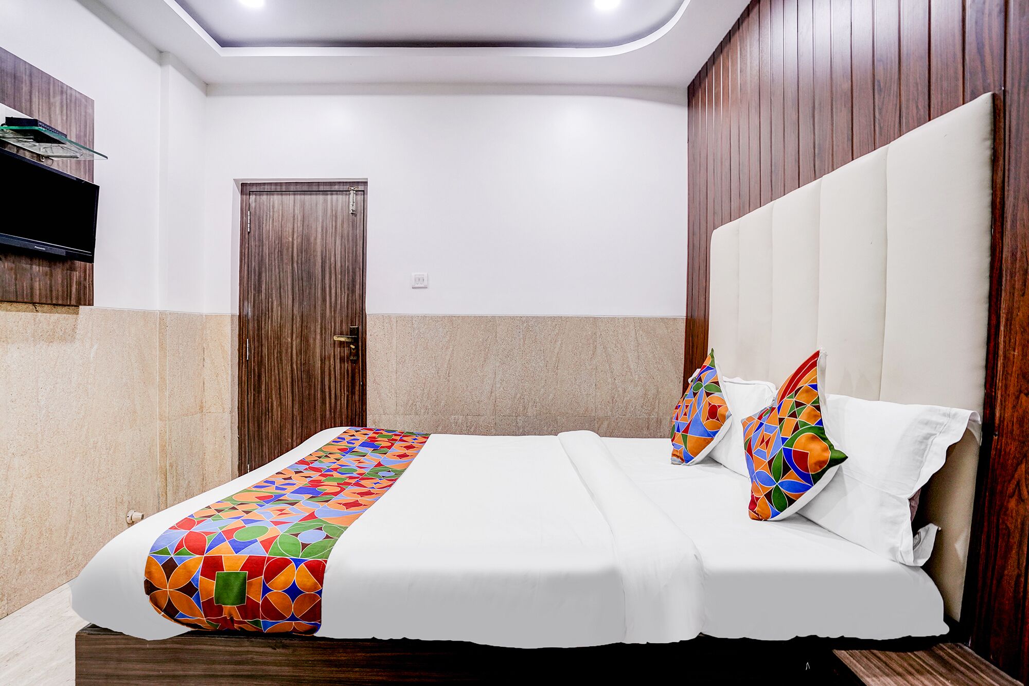 Ein Hotelzimmer mit einem Bett, einer Holztür und einem weißen Kopfende.