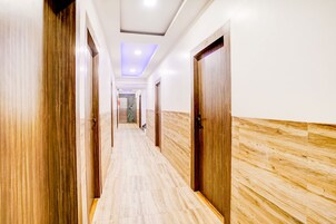 A corridor with wooden doors and a marble floor, leading to an elevator.