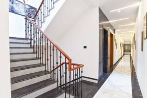 Un interno moderno con una scala, pavimentazione in marmo e un corridoio con quadri incorniciati.