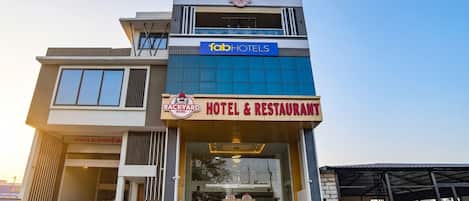 Un edificio de varios pisos con un letrero de hotel y restaurante en la planta baja.