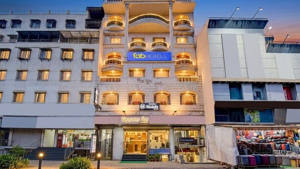 Ett hotell med flera våningar, balkonger, en skylt med texten ”Fab Hotels” och en tydligt markerad entré.