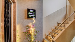 En trappa med en neonskylt med texten ”Malwa Motels” på väggen, som leder upp till första våningen.