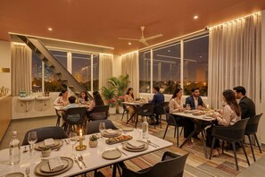 A dining area with tables set for guests, large windows, and a view of the cityscape. - Fabhotel Global Stay Rajajinagar (Bangalore)