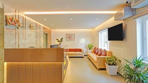 A modern living room with a reception desk, a sofa set, a flat-screen TV, and potted plants. - Fabhotel Global Stay Rajajinagar (Bangalore)