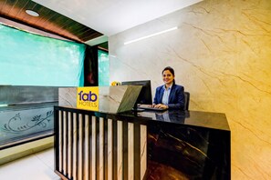 Un comptoir d’accueil d’hôtel avec un mur en marbre et une enseigne indiquant « fab hotels ».