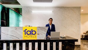 Un comptoir d’accueil d’hôtel avec un plan de travail en marbre, un ordinateur portable et une enseigne indiquant « Tab Hotels ».