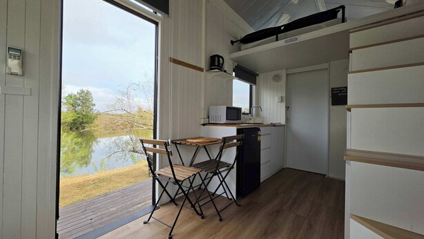 Et lille køkken med udsigt til en sø, et klapbord og et køleskab.