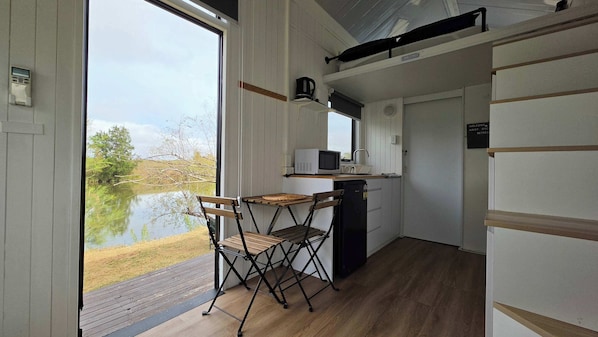 Une cuisine compacte avec vue sur un lac, une table pliante et un réfrigérateur.