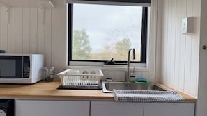 A kitchen with a microwave, sink, and window.