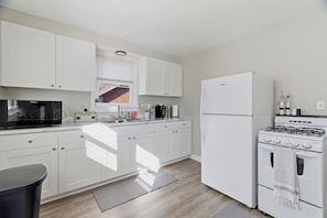 A modern kitchen with white cabinets, a microwave, a refrigerator, and a stove.