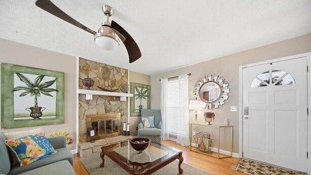 A living room with a fireplace, a ceiling fan, a sofa, a coffee table, and a door with a mirror. - 6 mi to Stone Mountain Park – Cozy Family Retreat (Snellville)