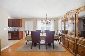 A dining area with a table, chairs, a chandelier, and a wooden cabinet. - 6 mi to Stone Mountain Park – Cozy Family Retreat (Snellville)