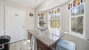 A kitchen with a granite countertop, a white door, and a window with a view of trees. - 6 mi to Stone Mountain Park – Cozy Family Retreat (Snellville)