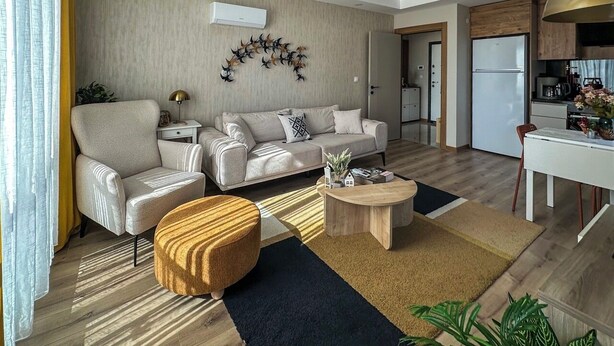 Ein modernes Wohnzimmer mit Sofa, Sessel, Couchtisch und Esstisch.