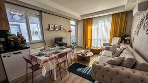 Ein modernes Wohnzimmer mit einer Couch, einem Esstisch und einer Küchenzeile.