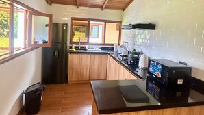 A kitchen with wooden cabinets, a black countertop, and a stainless steel refrigerator.