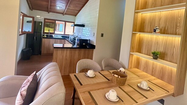 A cozy dining area with a wooden table set for four, a sofa, and a kitchen in the background.