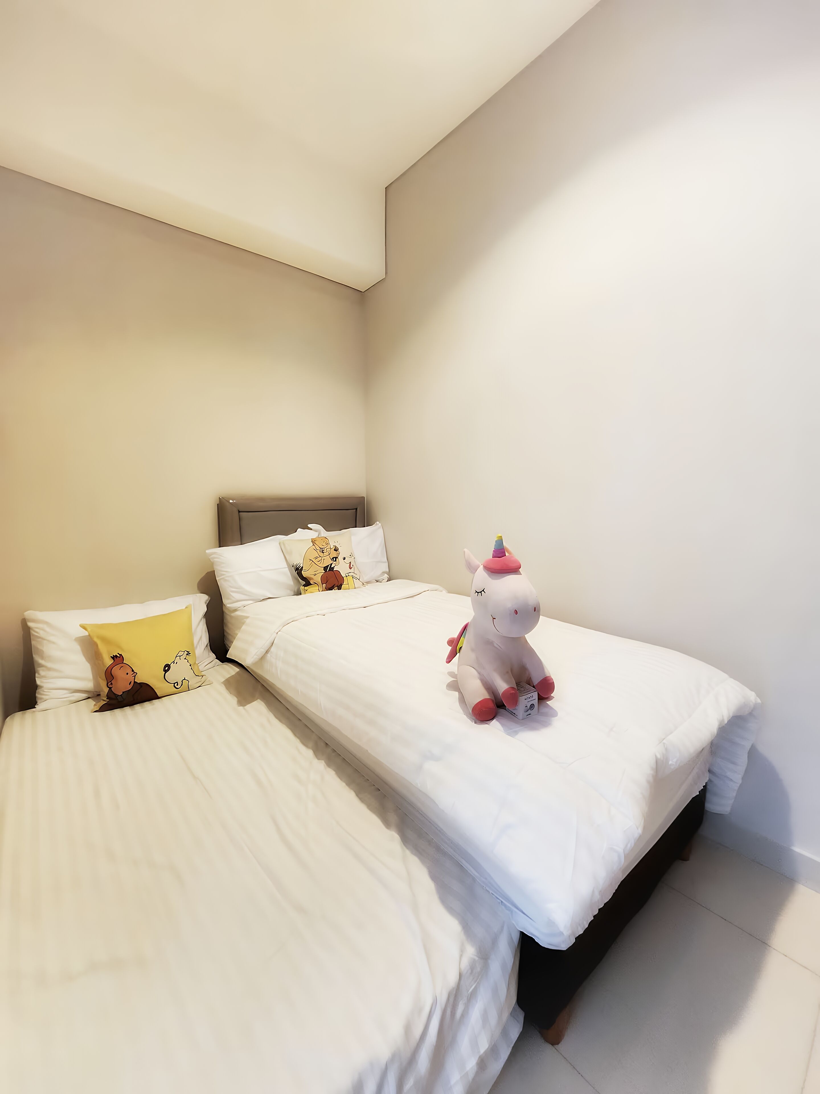 A bedroom with two beds, each with white bedding and a single pillow.