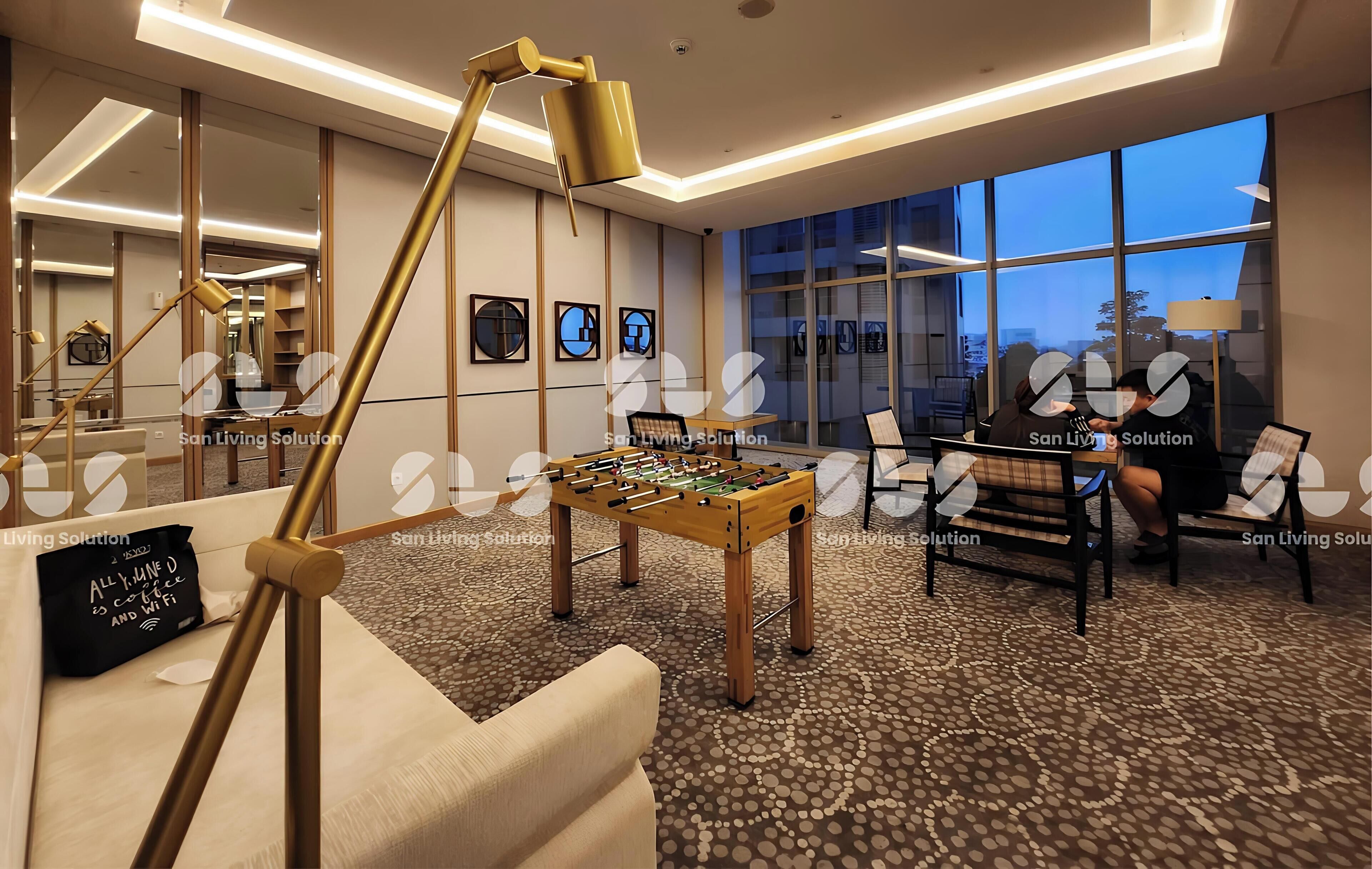A modern lounge area with a foosball table, comfortable seating, and large windows offering a view of the cityscape.