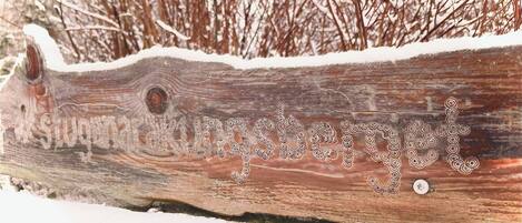 A wooden sign with the inscription "Stungberg" in a forested area with snow.