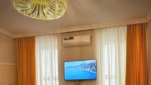 A room with a flat-screen TV mounted on the wall, air conditioning unit above it, and a wooden cabinet below. - Gold Perla De Mar Hotel (Baku)