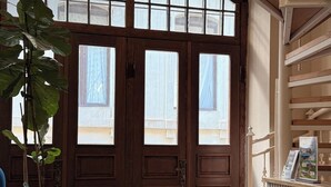A wooden door with a large window, a plant, and a blue chair. - Gold Perla De Mar Hotel (Baku)
