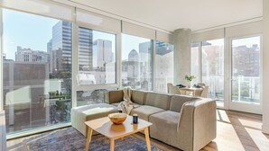 Ein modernes Wohnzimmer mit großem Fenster, einer Couch, einem Couchtisch und einem kleinen Beistelltisch.