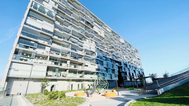 A modern multi-story building with balconies, a landscaped area with plants, and a clear sky. - Nordic home bliss with music moments (Helsinki)