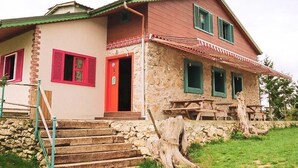 A two-story house with a stone facade, red shutters, and a wooden staircase leading to the entrance. - Kayaüstü Dağ Evi (Duzkoy)