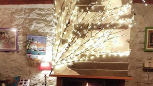A cozy room with a fireplace, a lamp, a chair, and a table. - Kayaüstü Dağ Evi (Duzkoy)