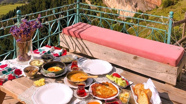 A table set with food and a view of a cliff. - Kayaüstü Dağ Evi (Duzkoy)