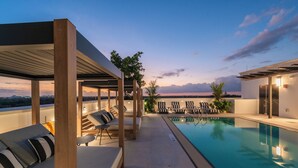 Uma área de piscina no terraço com espreguiçadeiras e um espaço de estar coberto.