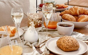 A breakfast setting with croissants, a bowl of jam, and glasses of white wine on a wooden table. - Villa Astoria Kühlungsborn (Kuehlungsborn)