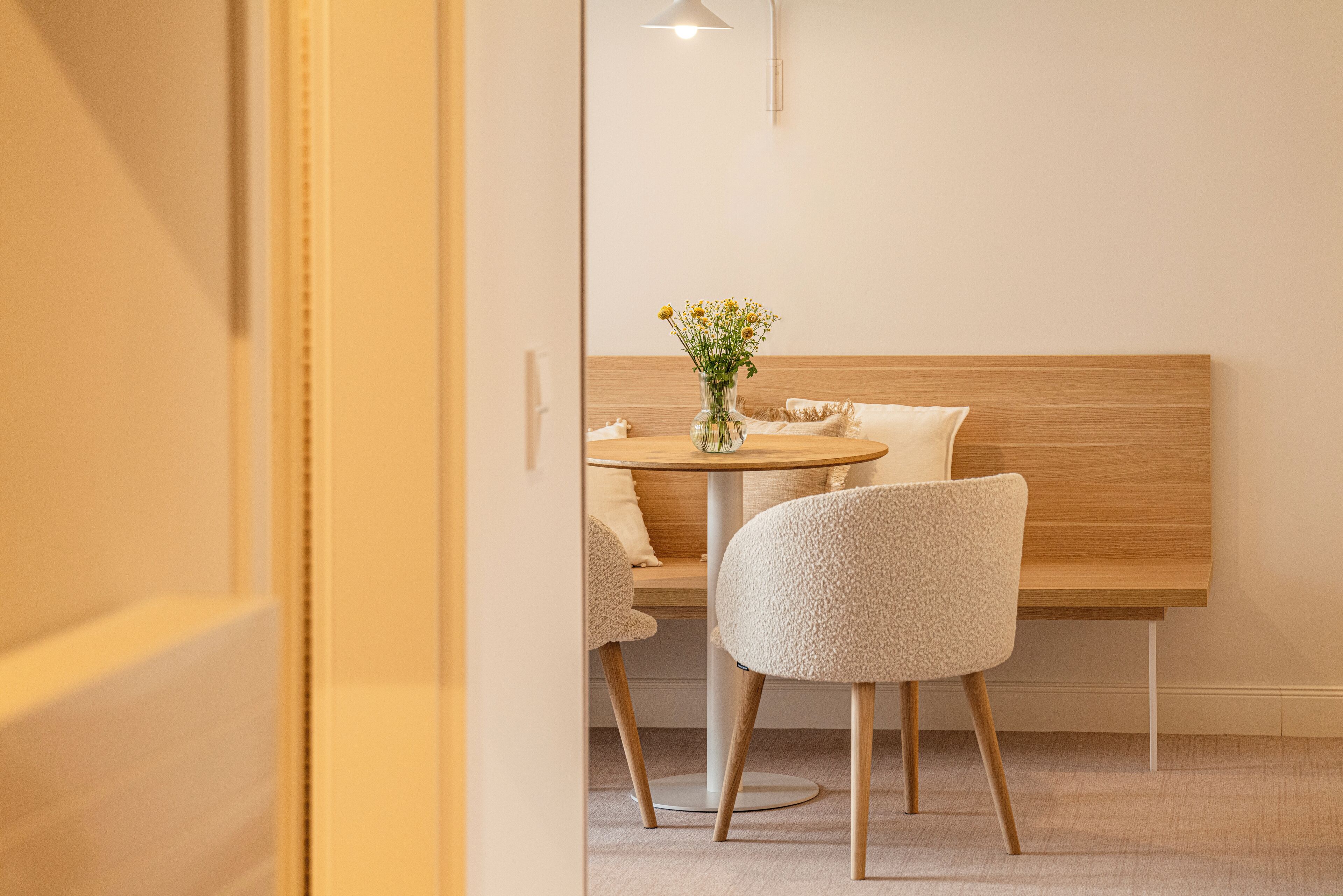 Ein modernes Zimmer mit einem hölzernen Kopfteil, einem runden Tisch und zwei Stühlen.