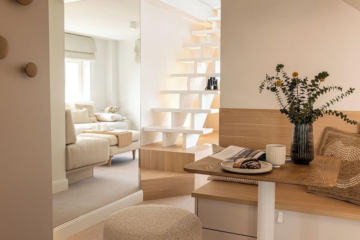 A modern, minimalist room with a wooden desk, a comfortable sofa, and a white shelving unit.