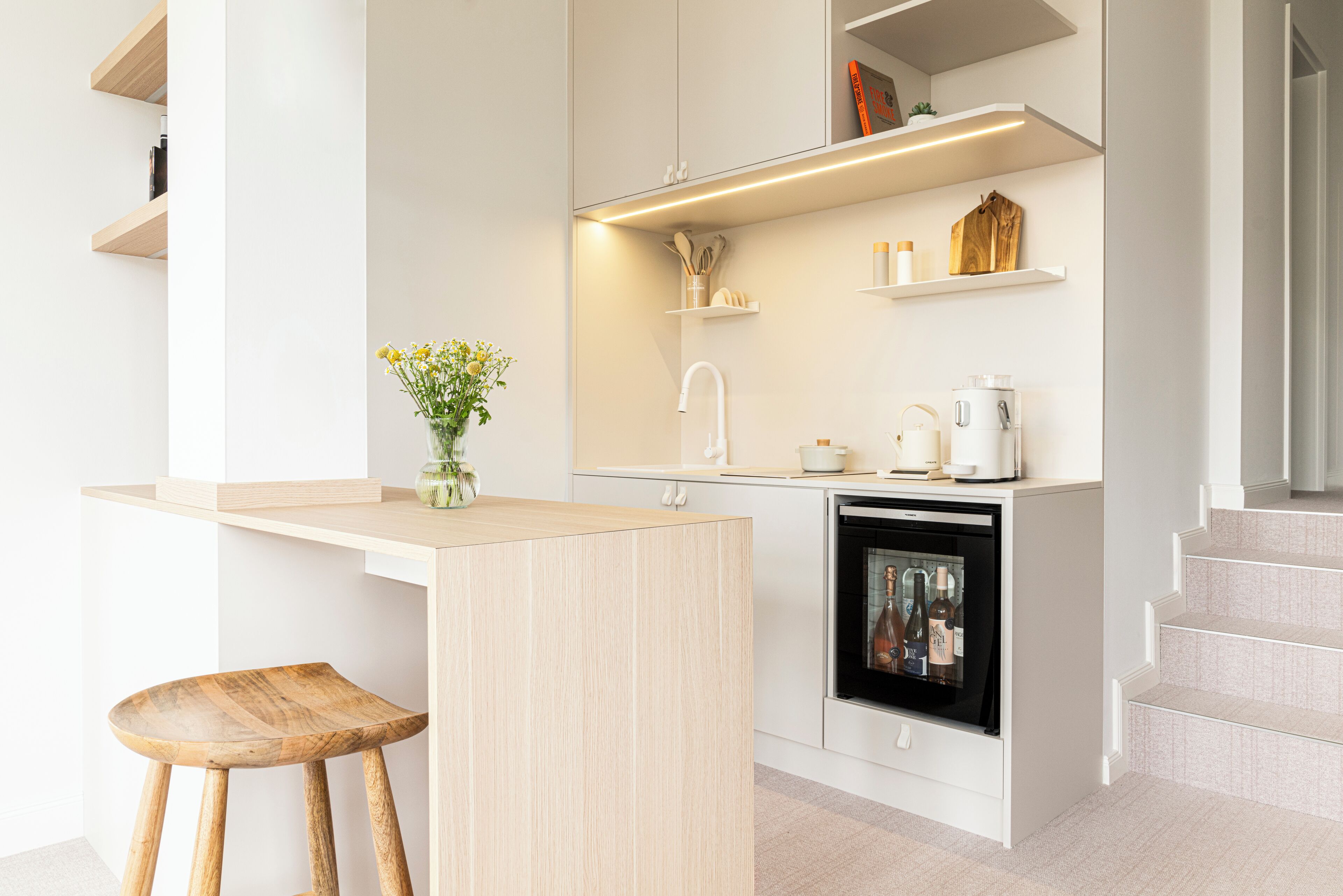 A modern kitchen with a wooden bar counter, a built-in oven, and white cabinetry.