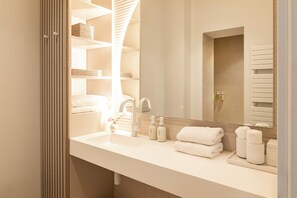 Un baño moderno con un lavamanos blanco, dos botellas de champú, un toallero y un espejo.