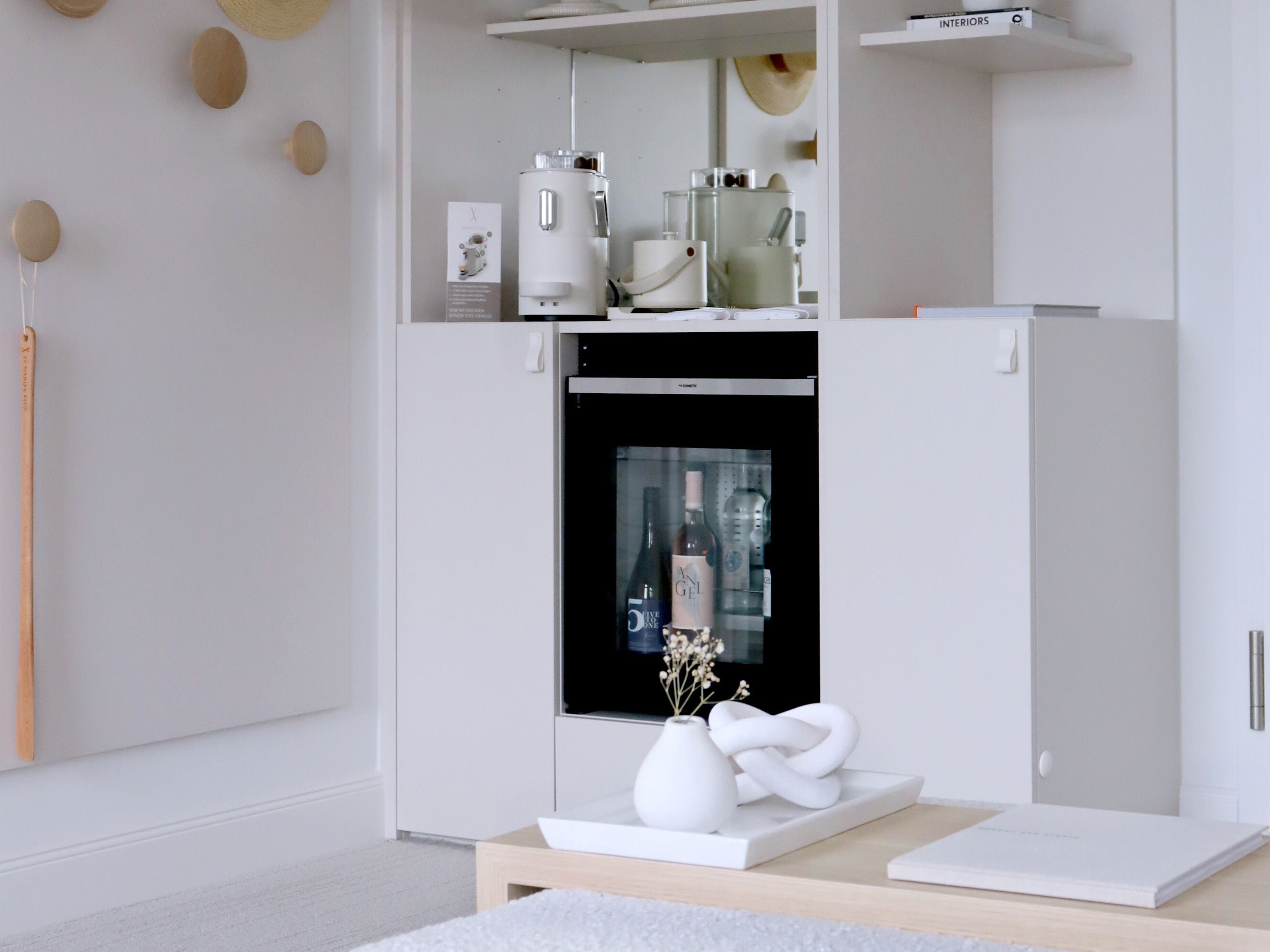 A modern, minimalist room with a built-in coffee machine, a refrigerator, and a glass display cabinet.
