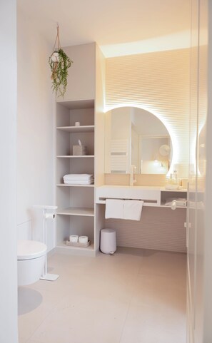 A modern bathroom with a toilet, shelves with towels, a sink with a mirror, and a hanging plant. - Villa Astoria Kühlungsborn (Kuehlungsborn)