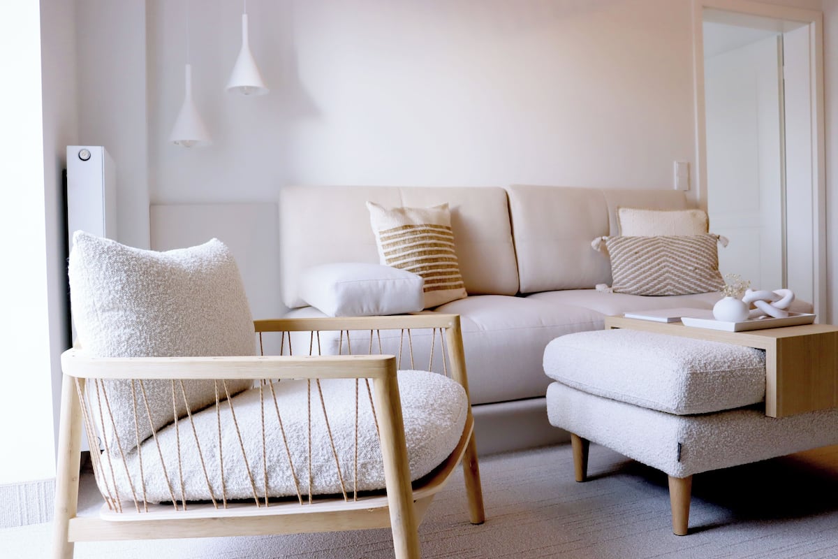 A modern living room with a sofa, a wooden chair, and a small side table.