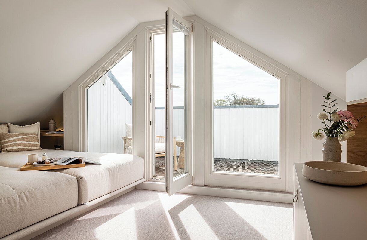 Ein Schlafzimmer mit einem großen Dachfenster, einem Bett, einem Nachttisch mit Tablett und Blick ins Freie.