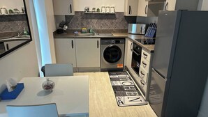 Eine kleine Küche mit Waschmaschine, Mikrowelle und Kühlschrank.