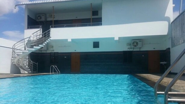 A swimming pool with a staircase leading to an upper deck. - Amman Cottage (Perundurai)